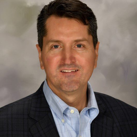 A man in a suit and tie smiling for the camera.